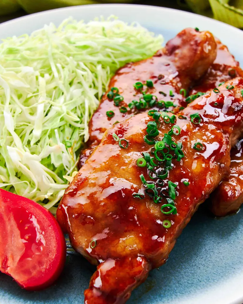 Glazed ginger pork slices with green onion beside shredded cabbage