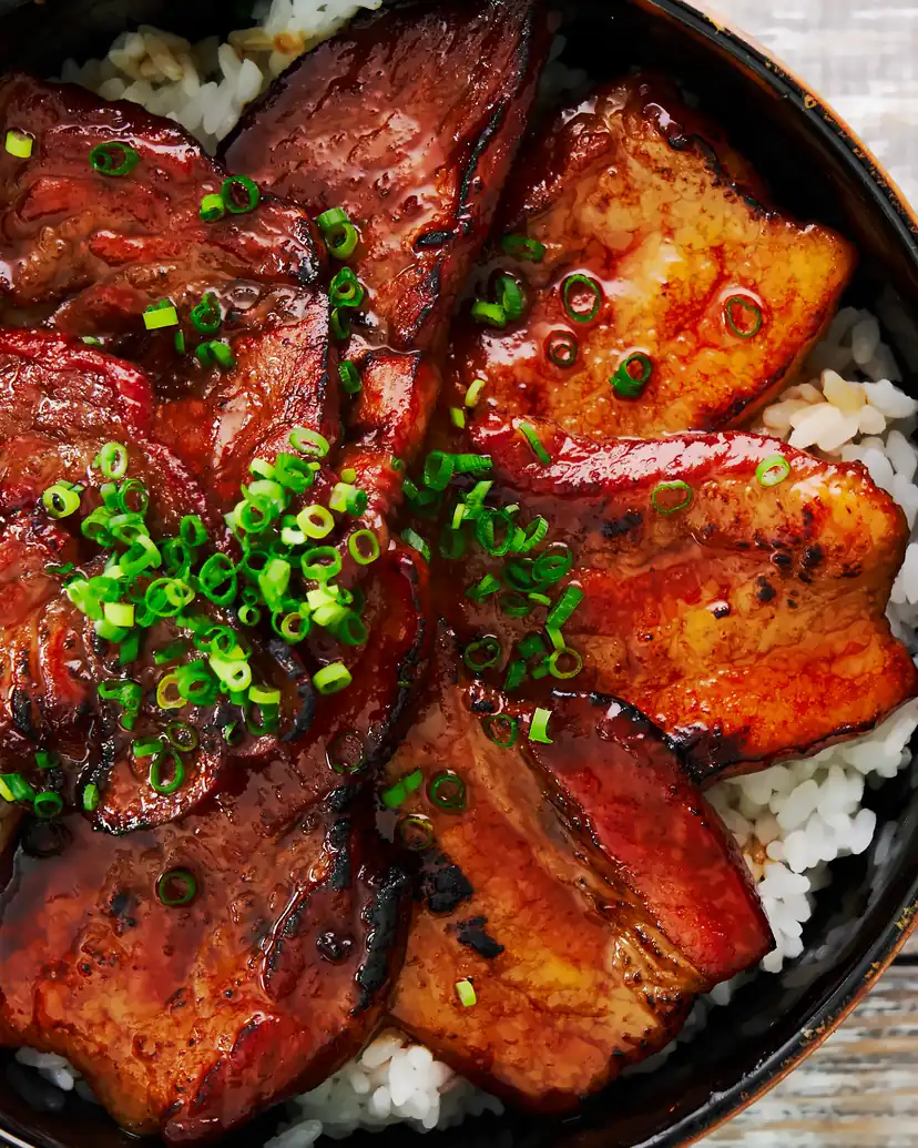 Glazed, charred slices of pork over white rice, topped with sliced green onion