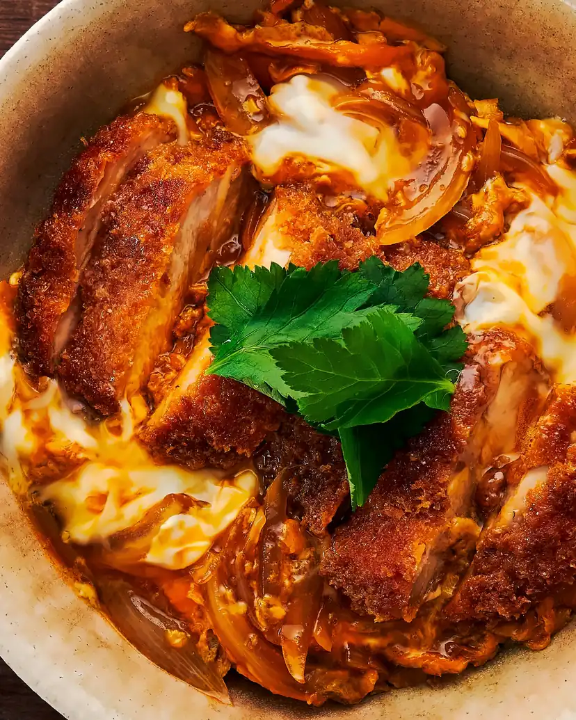 A chicken cutlet simmered with egg and onion over rice, topped with mitsuba