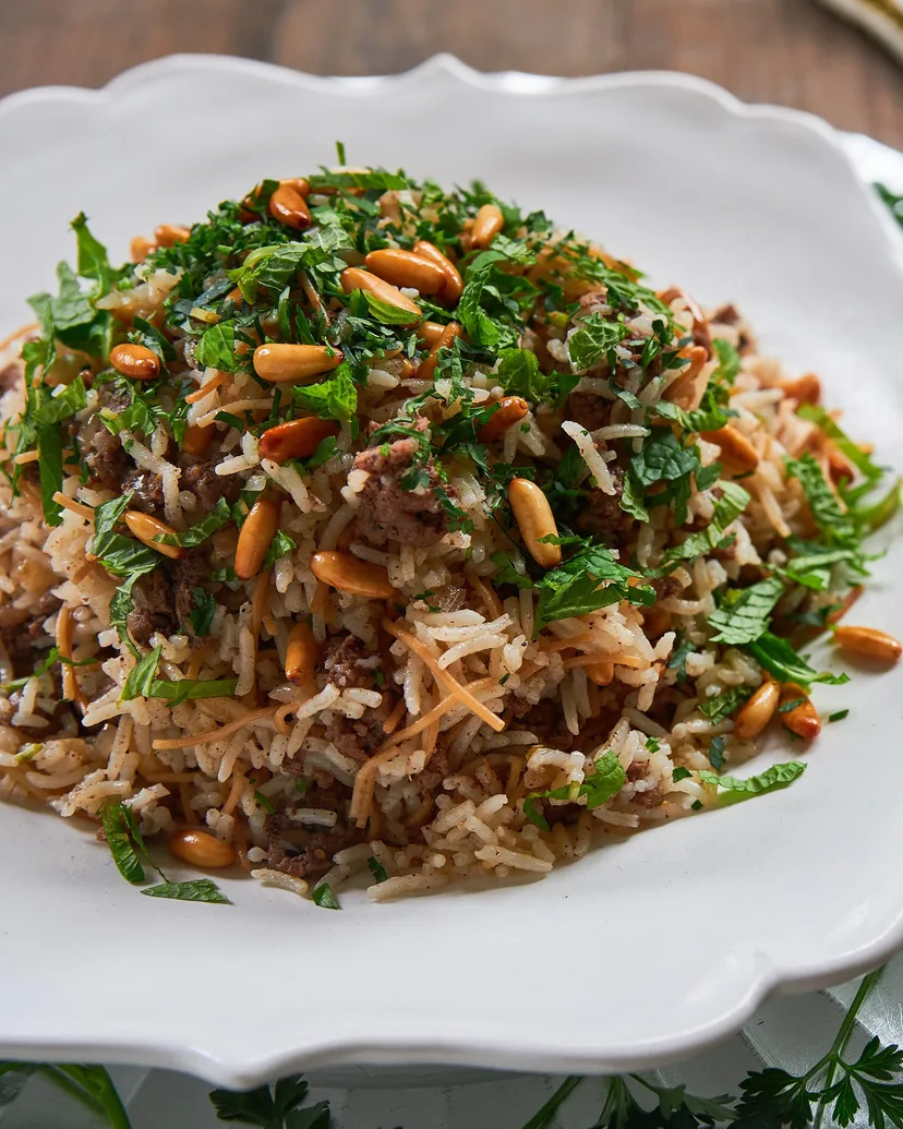 Spiced rice with ground lamb, toasted pine nuts and parsley on a scalloped white plate