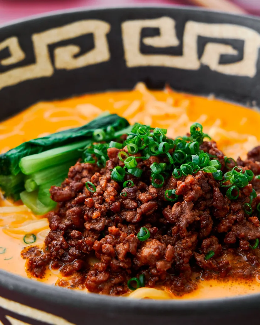 Tantanmen in an orange sesame broth with seasoned ground pork, bok choy and green onion