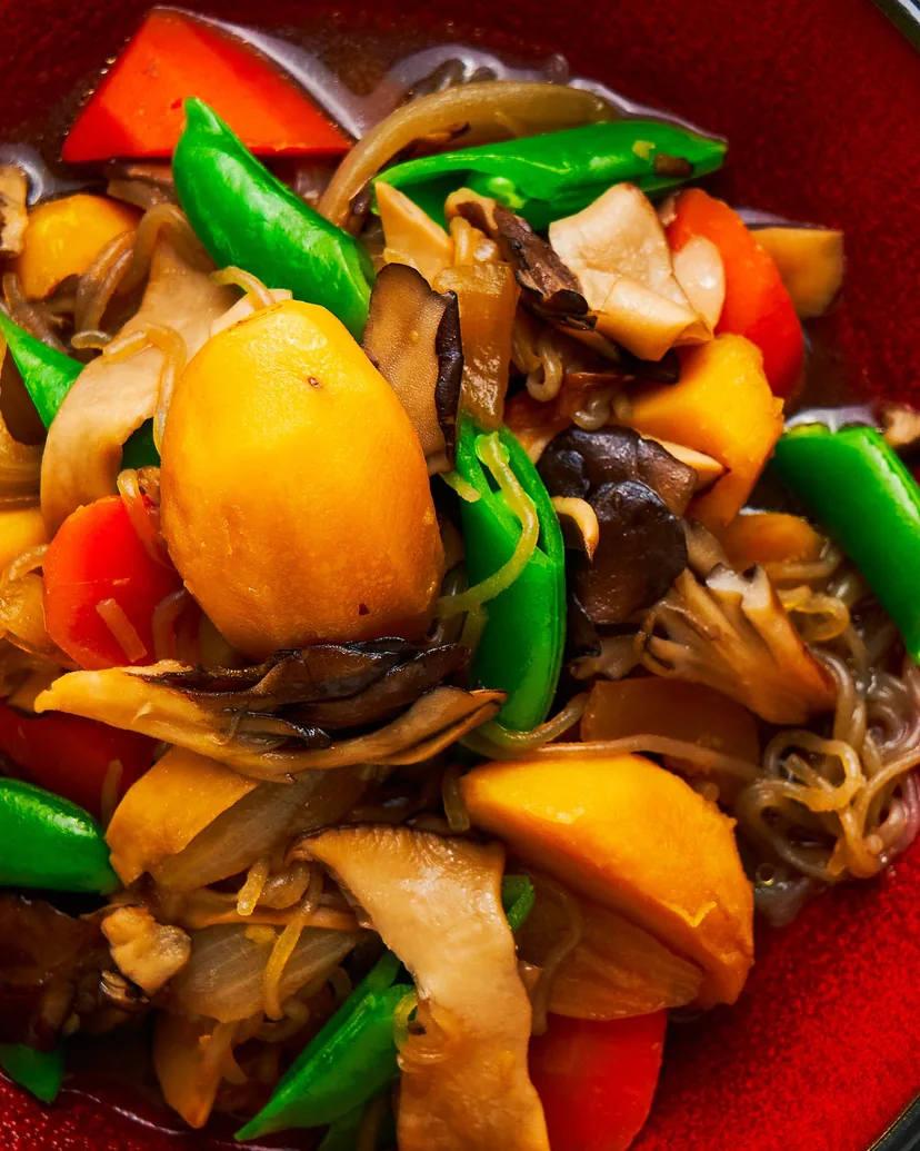 Potatoes, carrots, mushrooms, onion, snow peas and glass noodles simmered in a red bowl