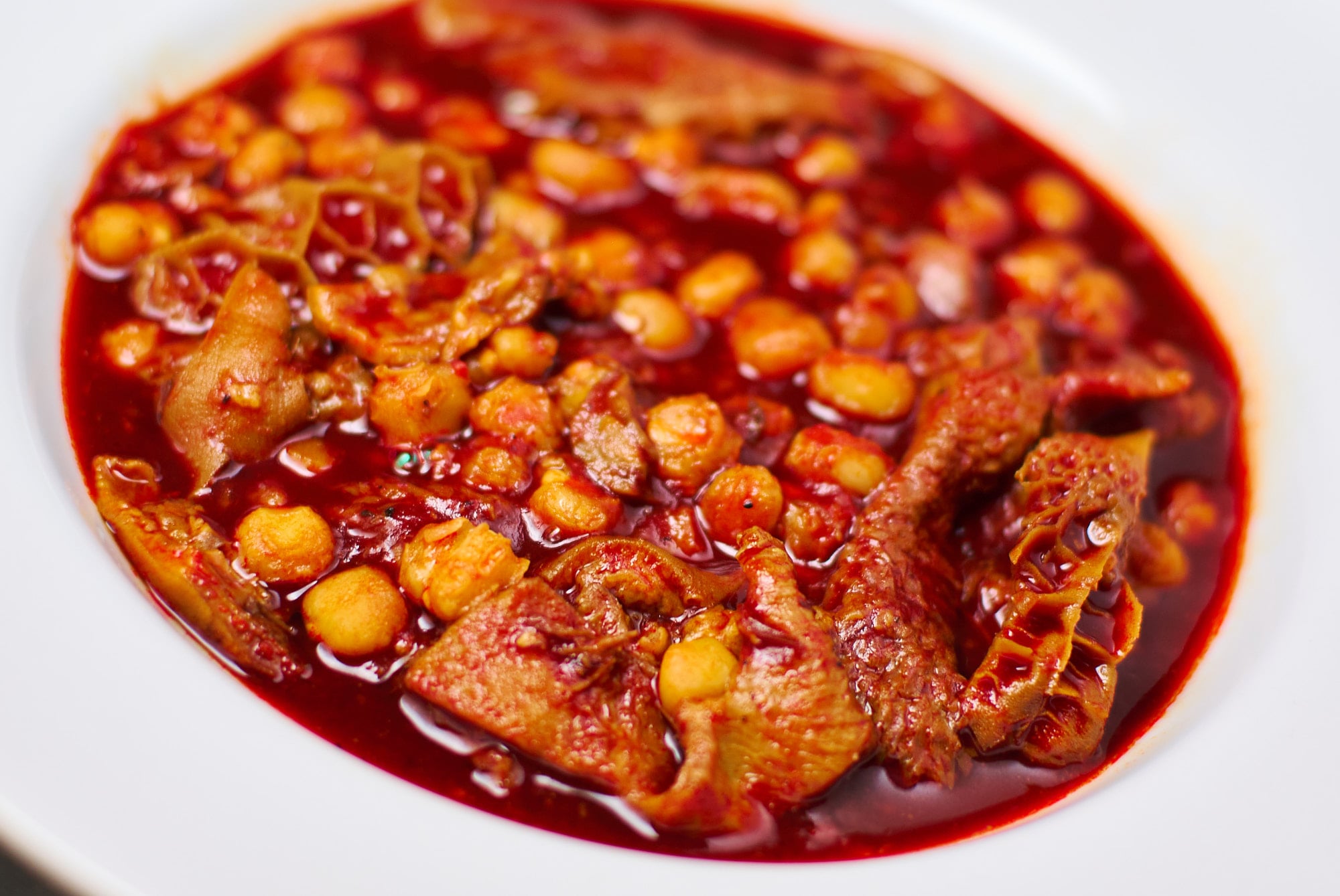 A white bowl of hearty Mexican Menudo (tripe stew).