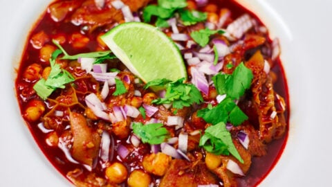 A vibrant tripe and pig trottter Menudo topped with red onions, cilantro and lime.