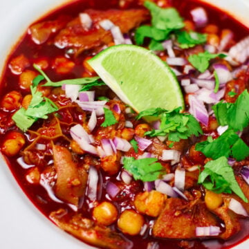 A vibrant tripe and pig trottter Menudo topped with red onions, cilantro and lime.