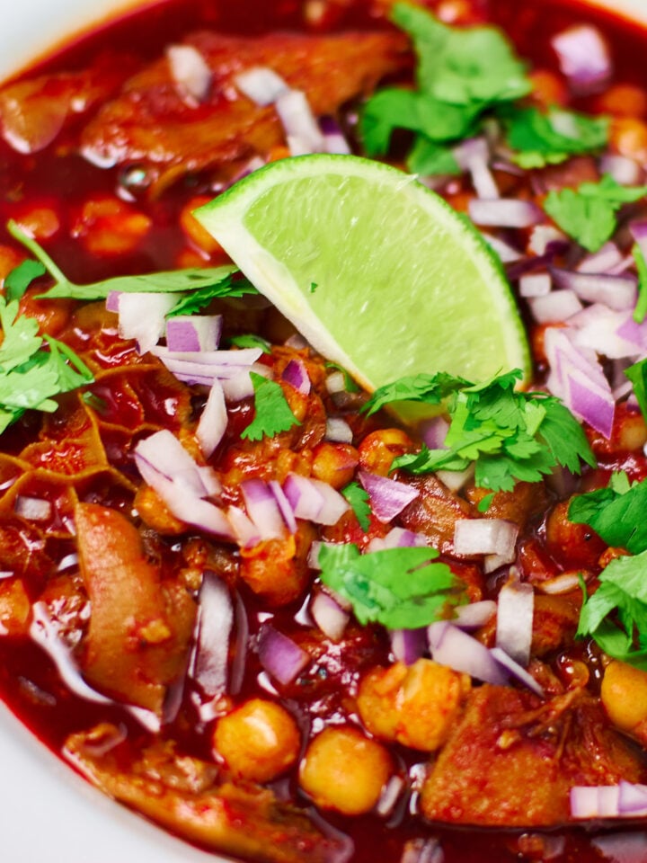 A vibrant tripe and pig trottter Menudo topped with red onions, cilantro and lime.