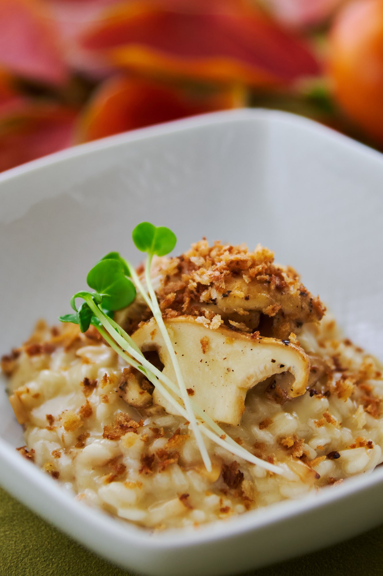 Close-up of matsutake risotto with a seared mushroom cap slices and microgreens, warm fall backdrop. - 1