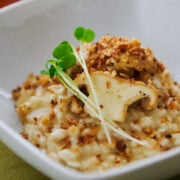 Close-up of matsutake risotto with a seared mushroom cap slices and microgreens, warm fall backdrop.
