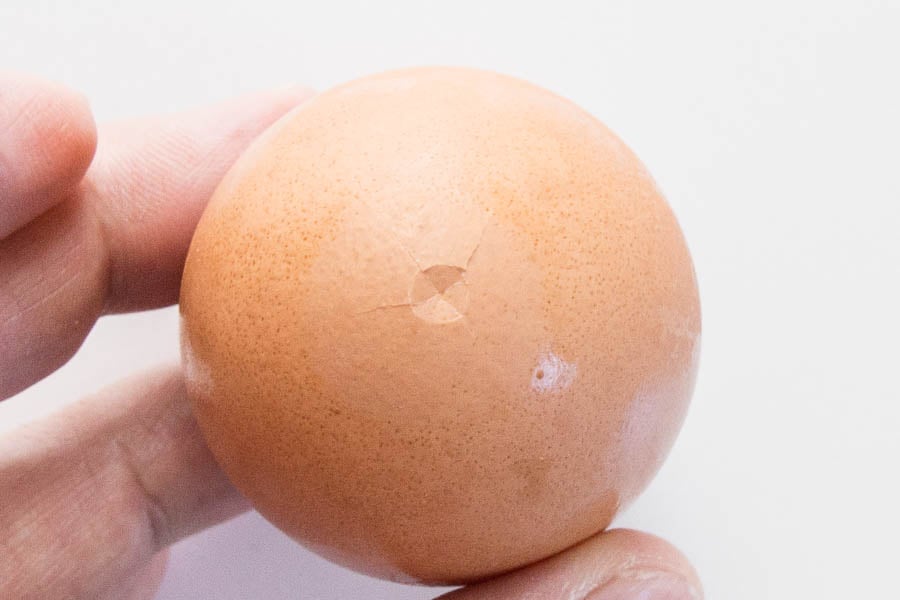 The trick to making easy to peel boiled eggs is to make a small circular crack in the bottom.