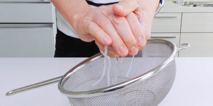 Squeezing water out of rehydrated glass noodles.
