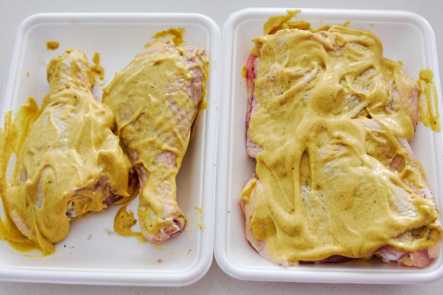 Bone‑in chicken legs slathered in tangy Dijon mustard marinade lounge on a tray, promising succulent flavor in every bite.