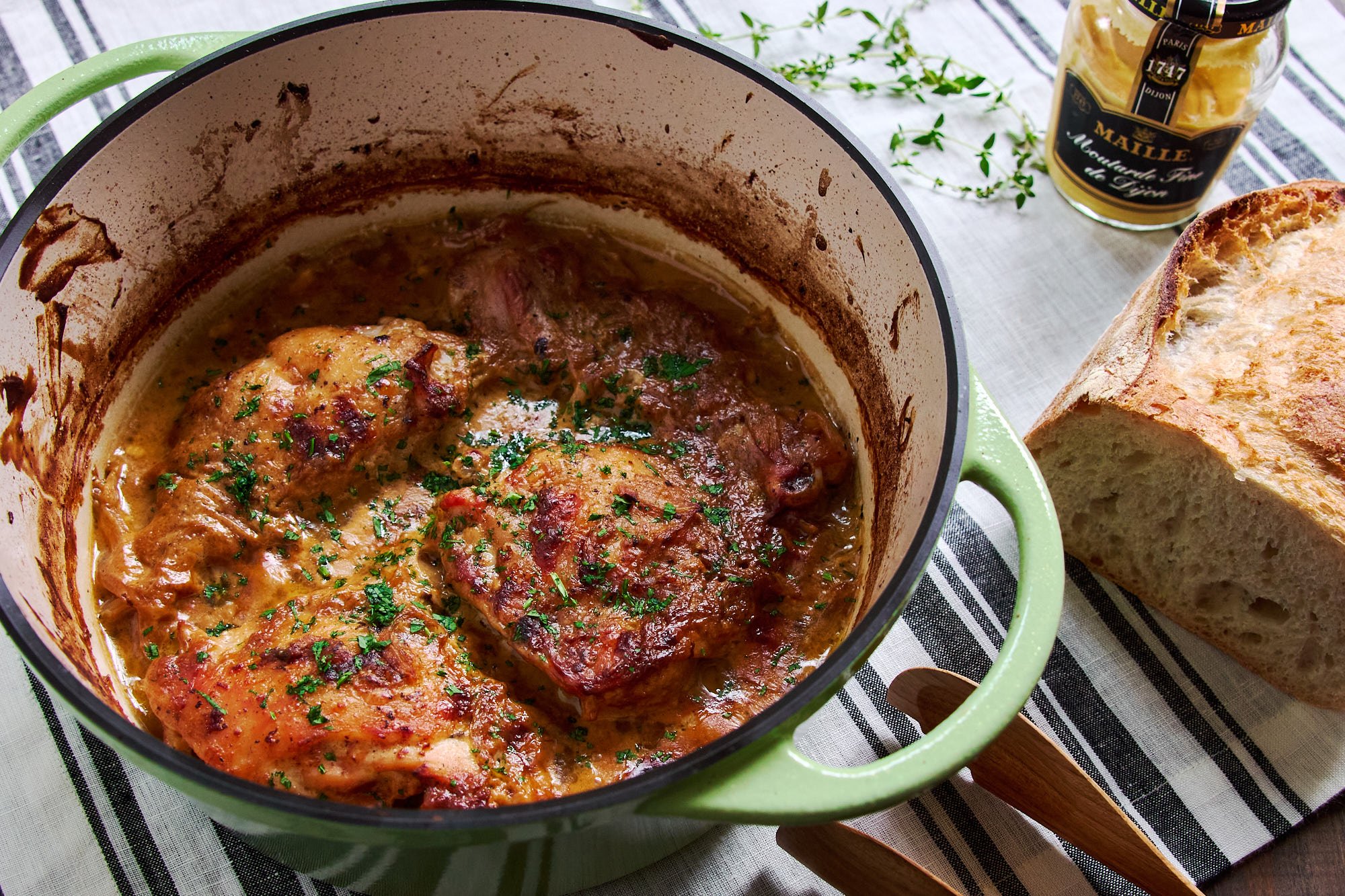 The finished Poulet à la Moutarde rests in a green Dutch oven-fall‑apart tender, parsley‑speckled, and ready to be scooped up with crusty bread. - 2