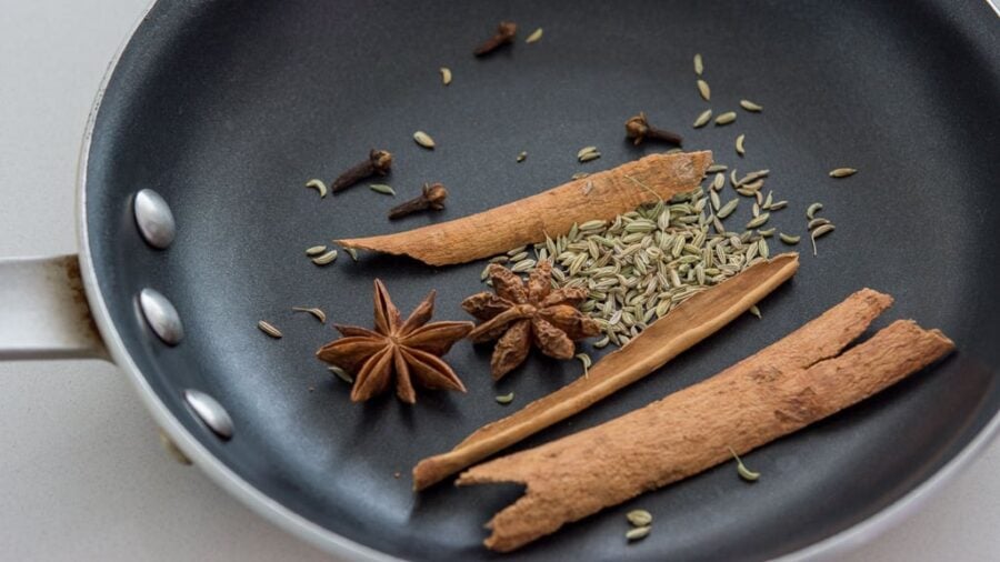 Spices toasting in a pan.