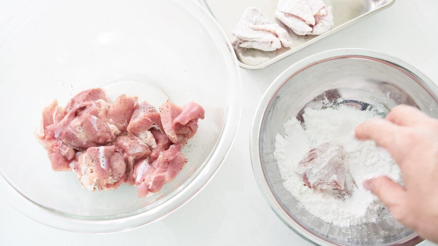 Dusting the marinated chicken in potato starch for making lemon chicken.