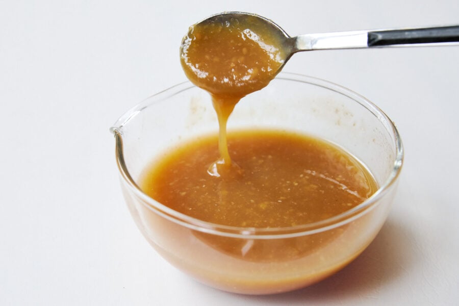 Spoon drizzling miso marinade into a glass bowl, showing glossy texture for miso salmon.