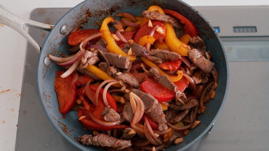 Stir-fried Lomo Saltado in a frying pan.