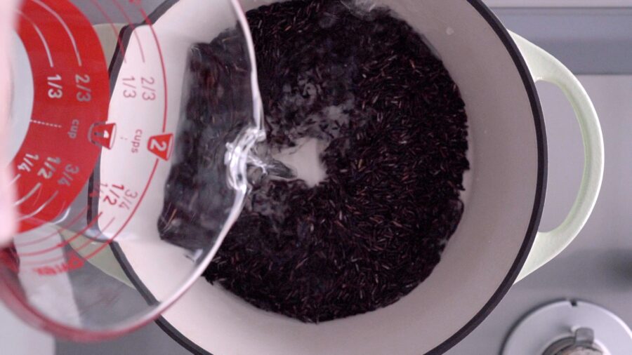 Adding water and Riceberry to a heavy bottomed pot.