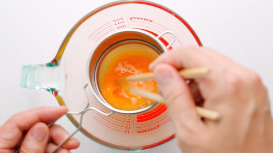 Straining eggs through sieve to remove bubbles.