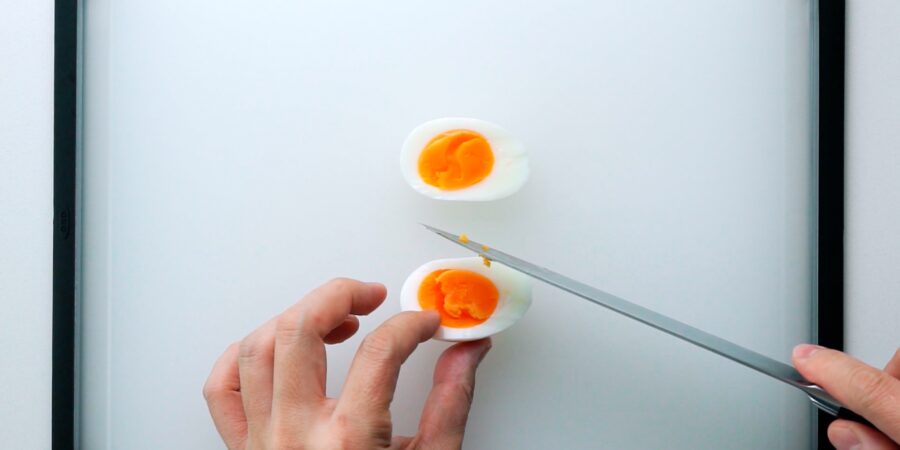 Cutting a medium boiled egg in half for a sandwich.