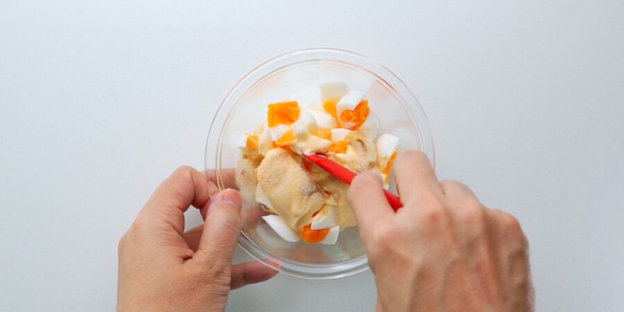 Mixing chopped boiled eggs along with Japanese mayonnaise and seasonings to make an egg salad.