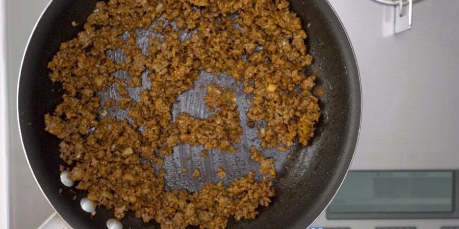 Curry flavored ground beef cooking in a frying pan.