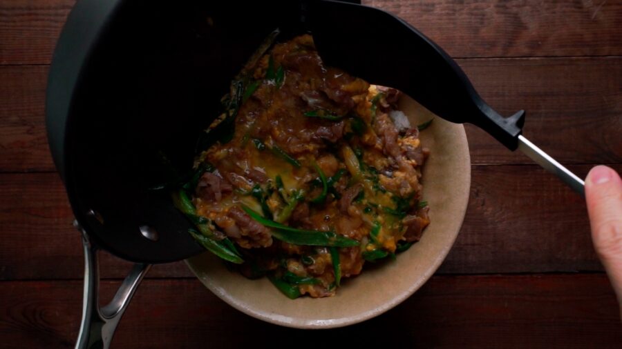 Sliding beef and egg onto the donburi of rice.