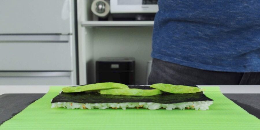 Placing sliced avocado on nori.