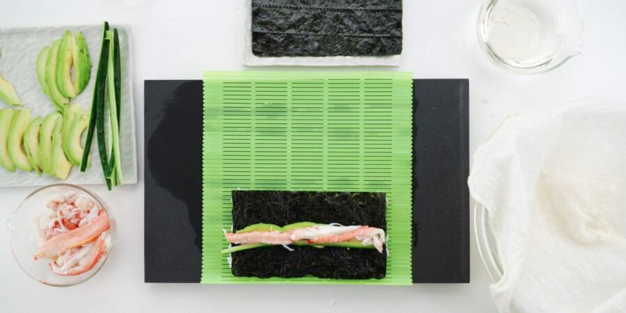 Ingredients for California Roll on a sushi mat.