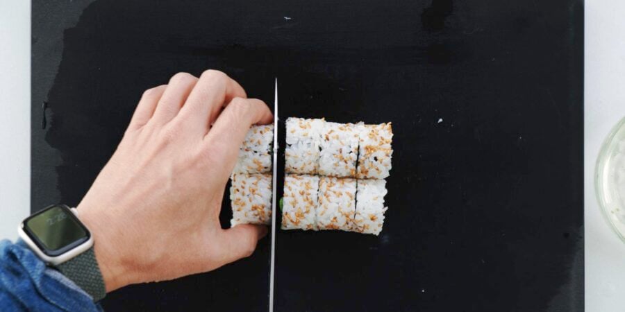 Cutting California Roll into bite-sized pieces.