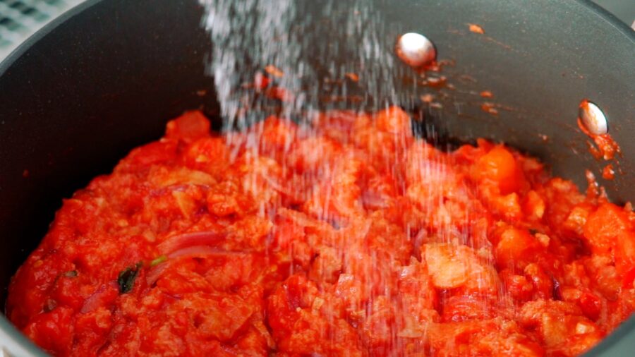 Seasoning a pot of Tuscan Bread and Tomato Soup with salt.