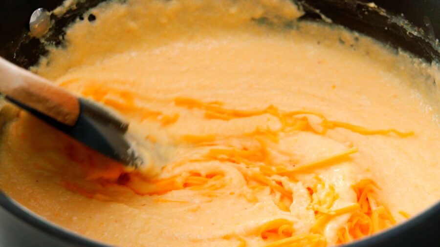 Melting cheese into a pot of grits.