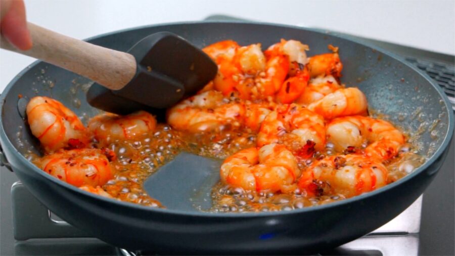 Honey garlic sauce caramelizing around shrimp in a pan.