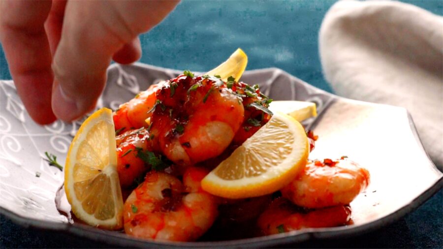 Garnishing honey garlic shrimp with lemons.