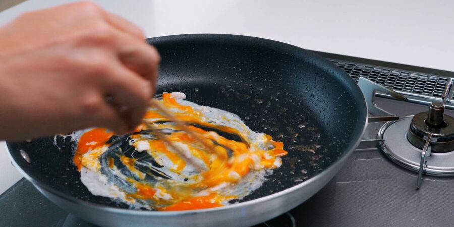 Scrambling egg in a frying pan.