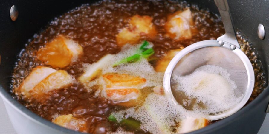Skimming chicken broth for Japanese udon noodle soup.