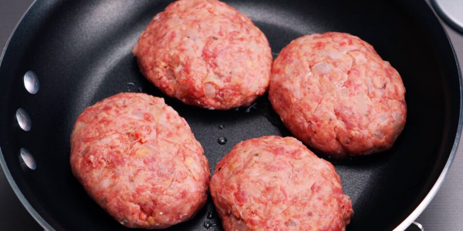 Raw hamburg steaks in a frying pan.