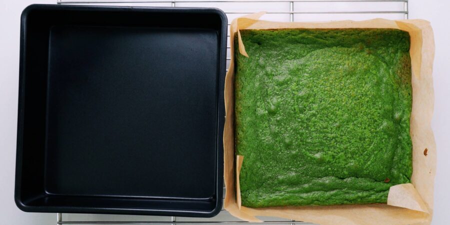 Matcha brownies next to pan on a cooling rack.