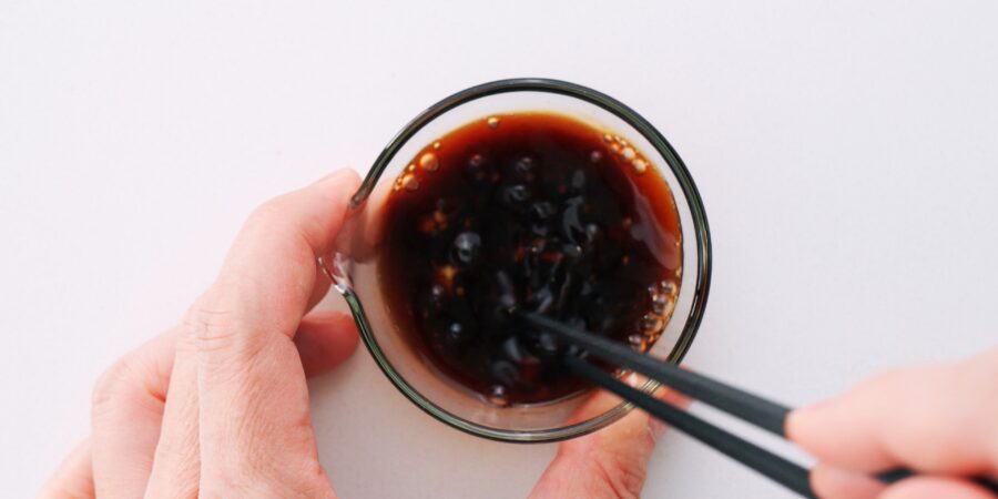 Whisking sushi bowl sauce in a glass bowl with chopsticks.
