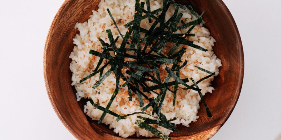 Sushi rice, nori and sesame seeds in a wooden bowl.