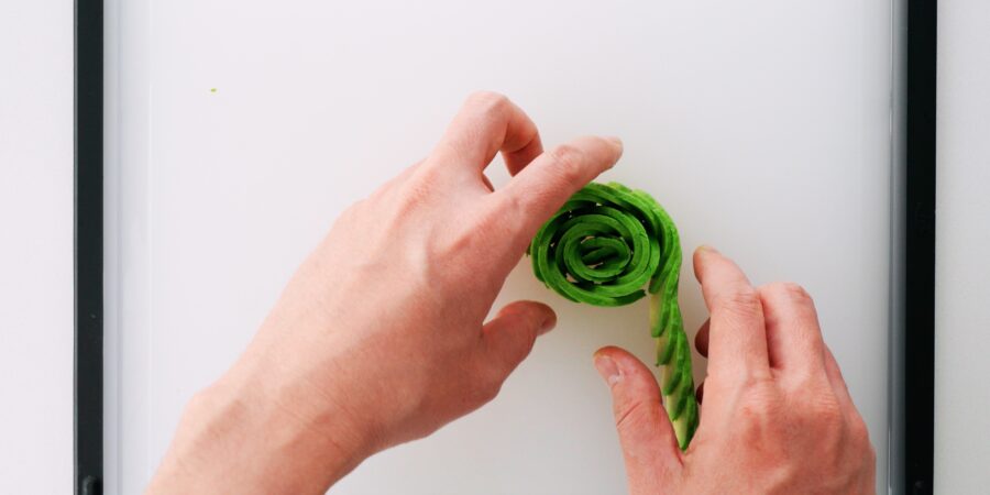 Rolling sliced avocado to make a rose.