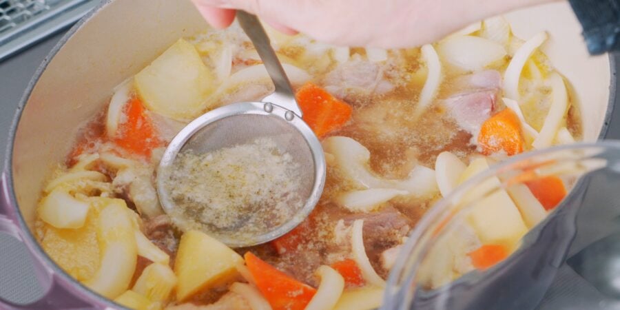 Removing oil and scum from stew.