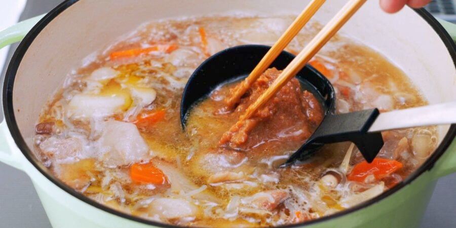 Stirring miso into a ladle of soup broth.