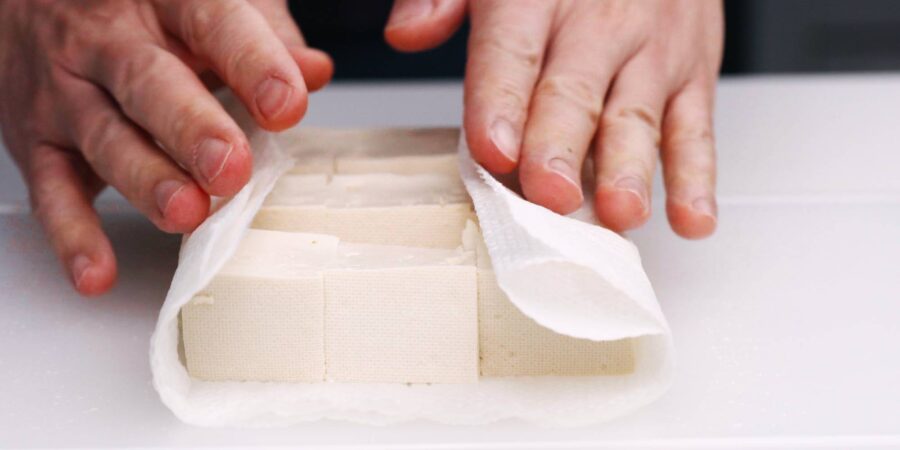 Drying cubes of tofu using paper towels.