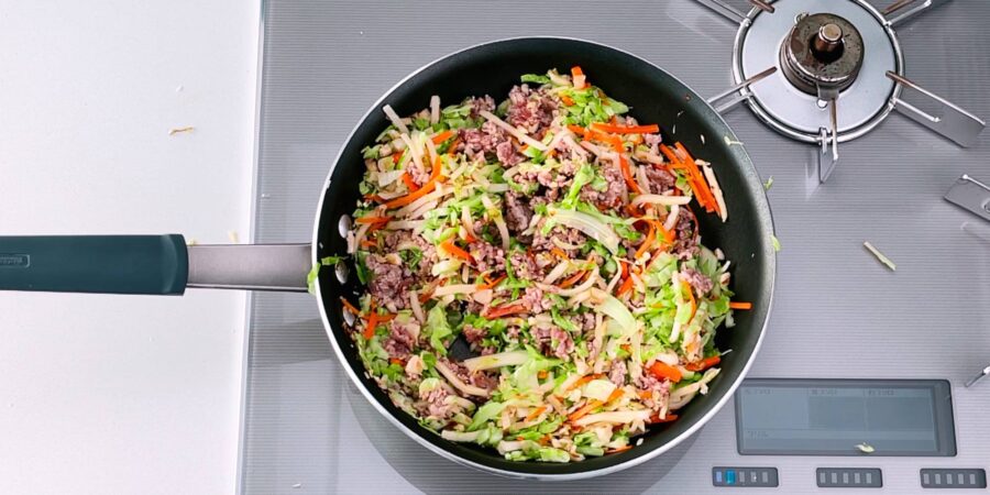 Vegetables and meat stir-frying for making Japanese spring rolls.