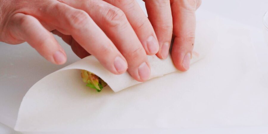 Rolling spring roll wrapper over spring roll filling.