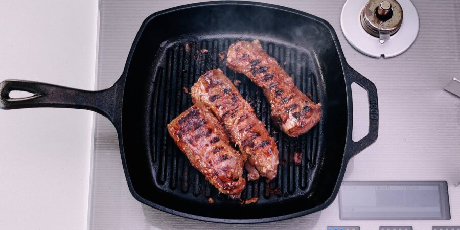 Overhead shot of hanger steaks on grill pan with grill marks.