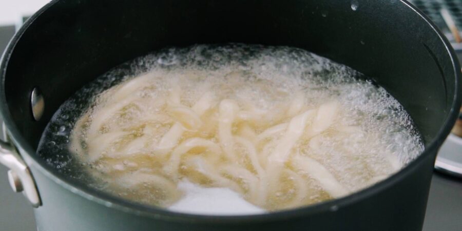 Udon noodles boiling in a pot.