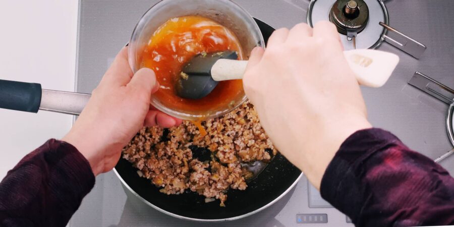 Stirring Mapo Tofu sauce and adding it to the pan.