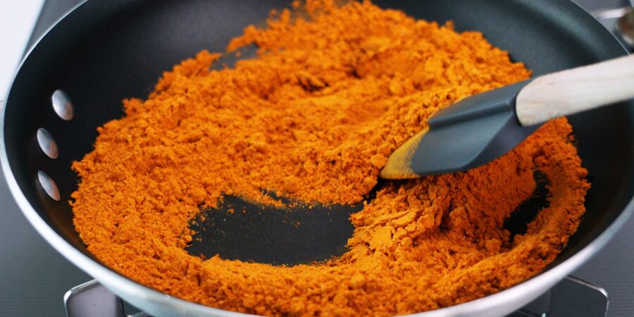 Toasting curry powder in a frying pan.