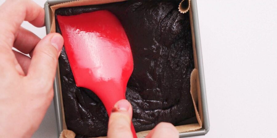 Chocolate mochi being pressed into a square mold.